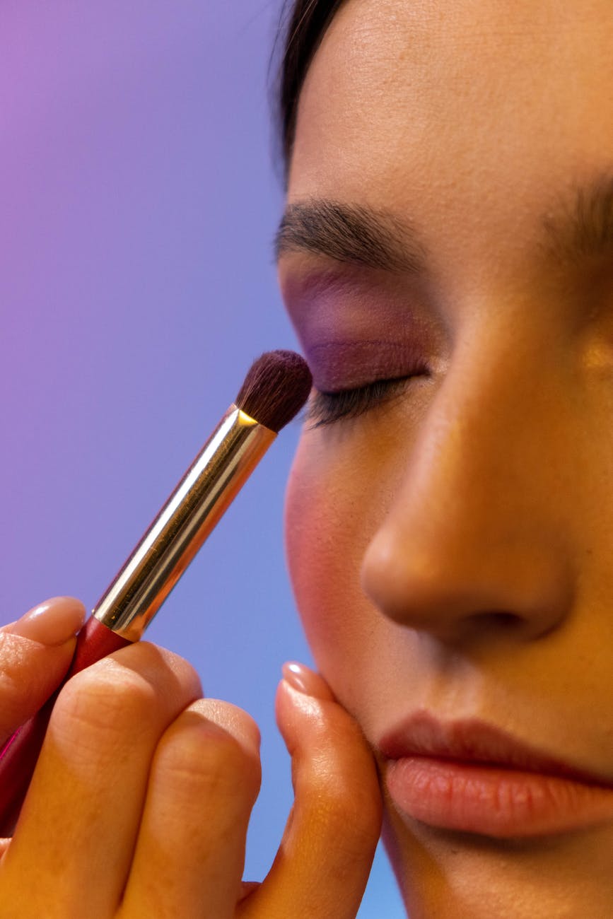 a person applying eyeshadow to a woman