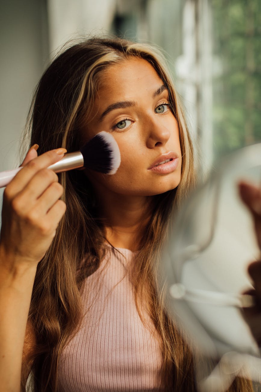 young woman applying makeup using cheek brush