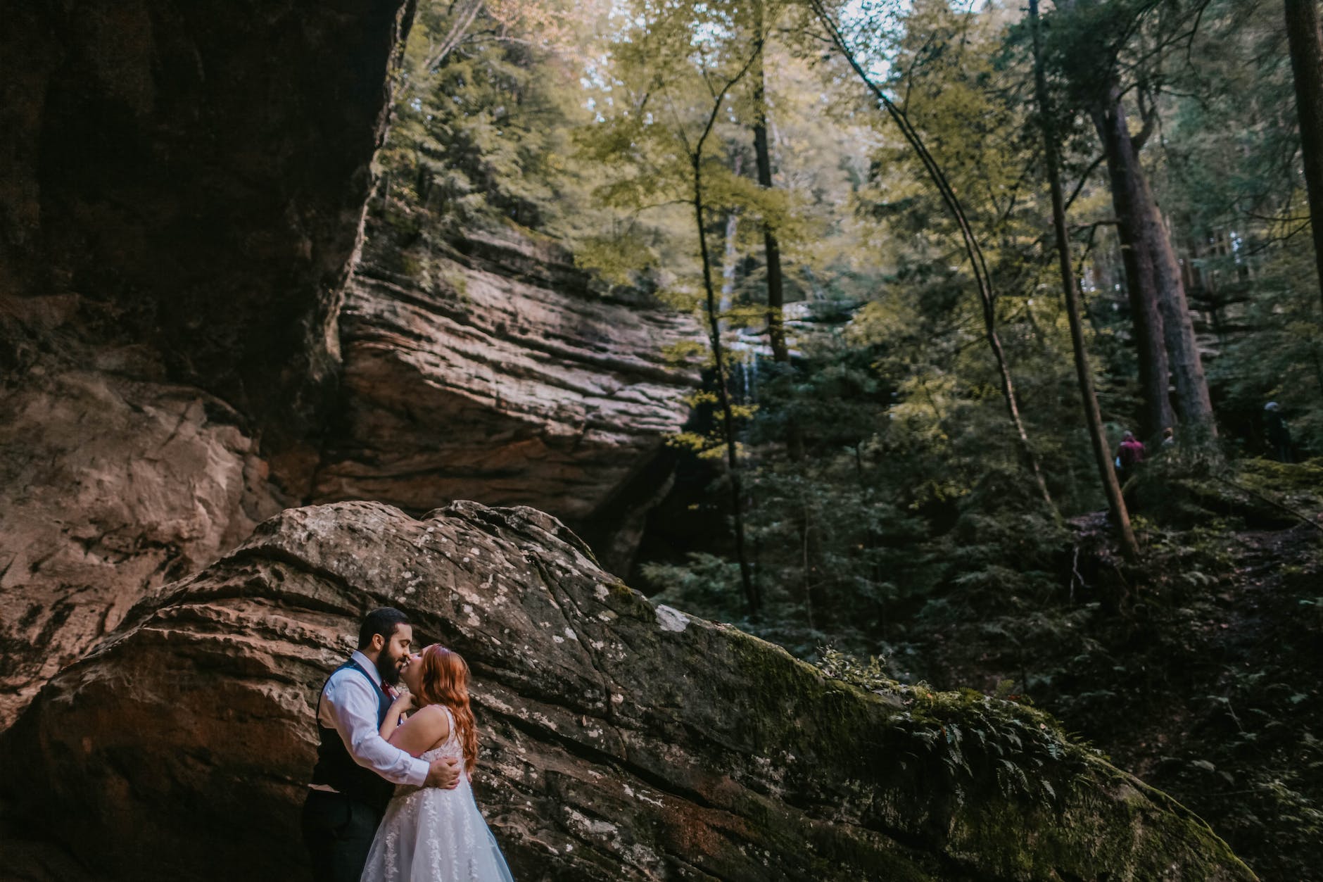 wedded couple kissing under cliff