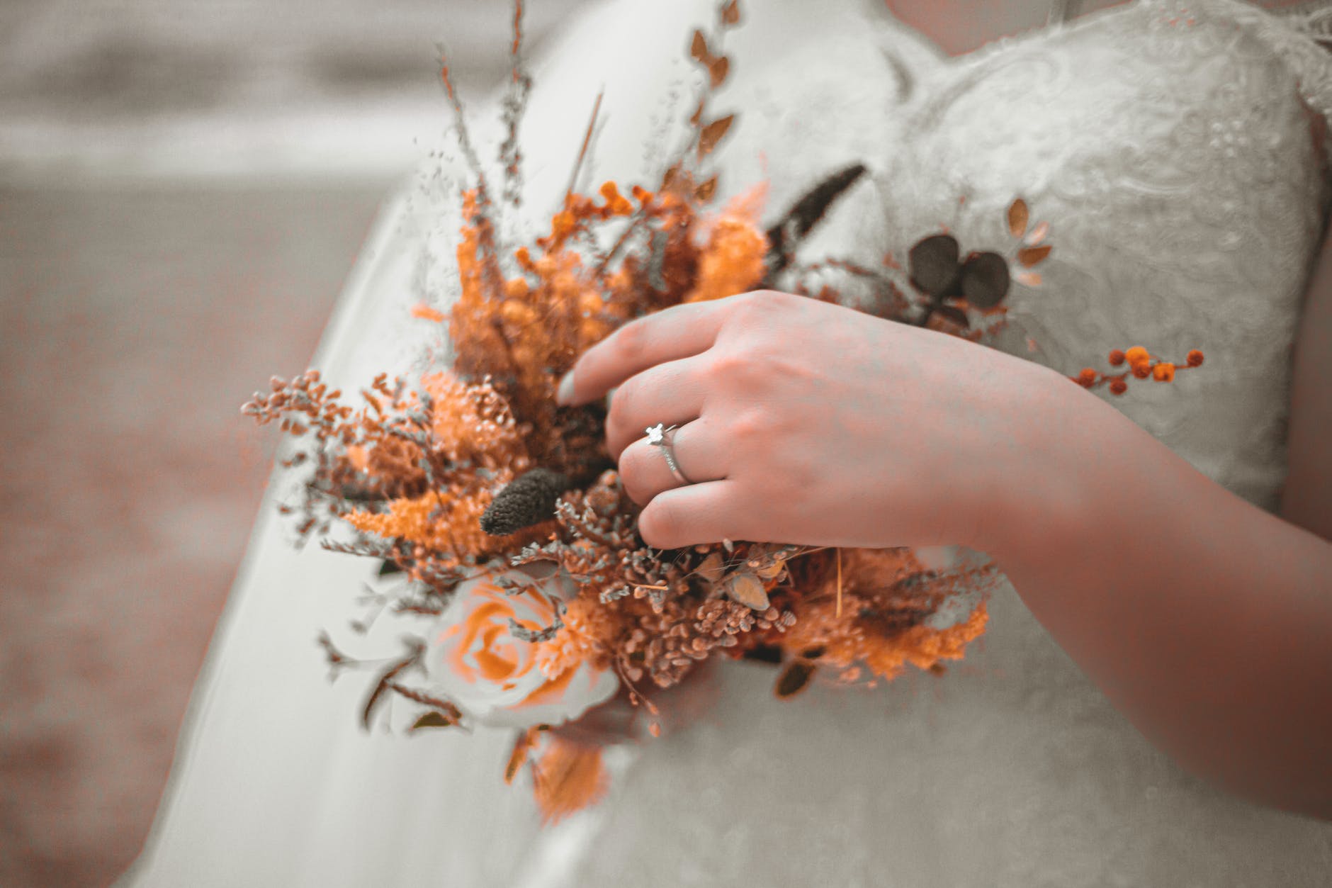 bride in white dress touching wedding bouquet