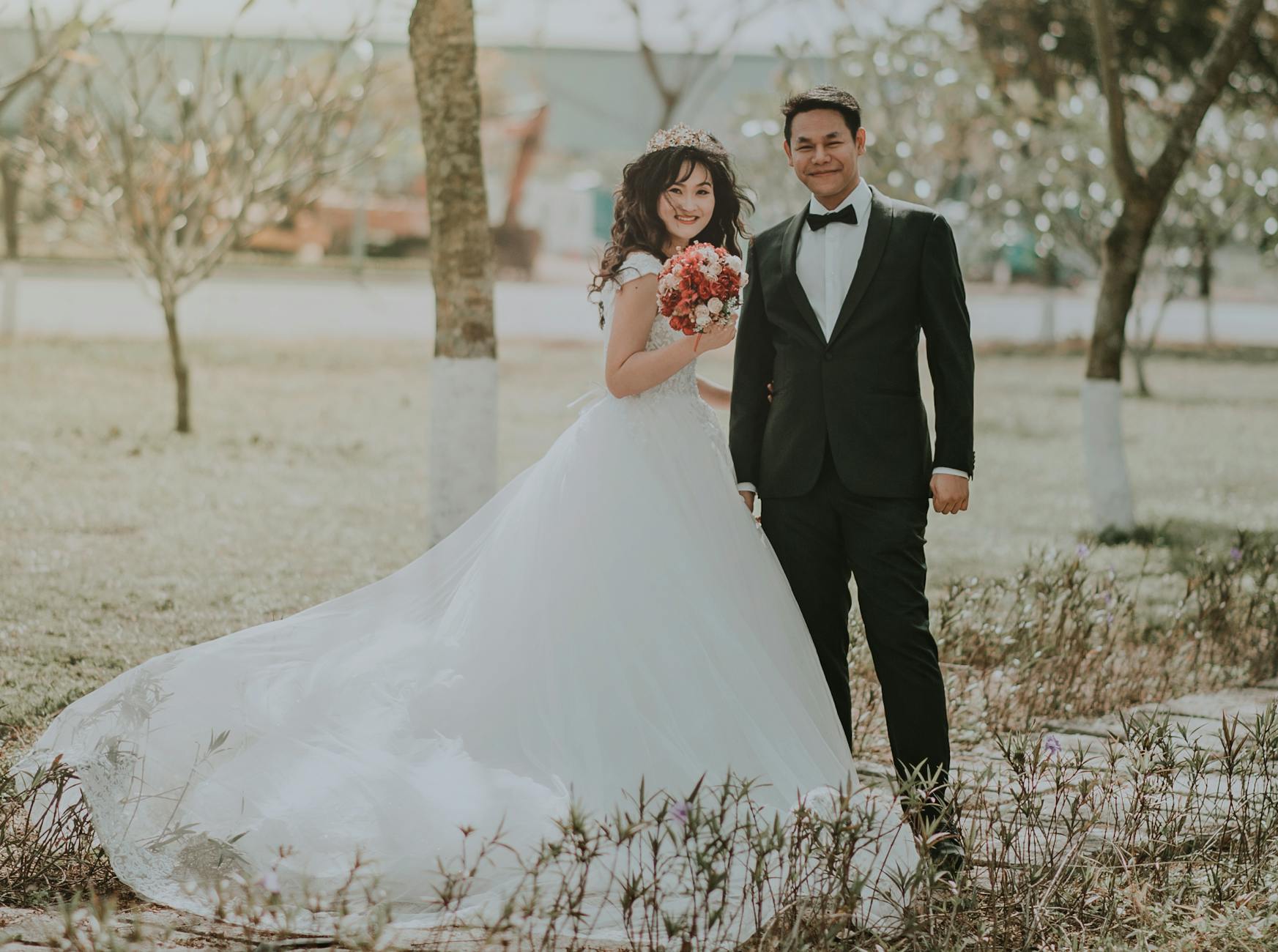 woman wearing white wedding ball beside man wearing black notch lapel suit on pathway near the green grass field